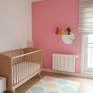 Ay yıldız raf pembe duvarlı bebek odasında; uyuyan yüzlü beyaz ay, gri yıldız ve rafta flamingo, ananas, kaktüs süsler