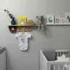 Ayı duvar askısı bebek odasında raf altında; kahverengi ayı başı ve askıda isim yazılı beyaz bebek kıyafeti