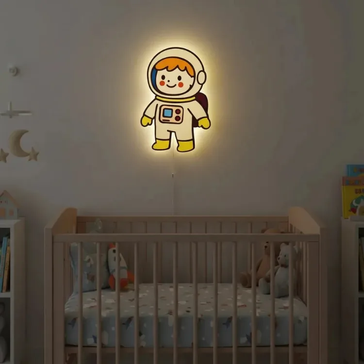Erkek astronot ahşap gece lambası, loş bebek odasında beşiğin üstünde ışığı açık, yanında ay ve yıldız süsleri