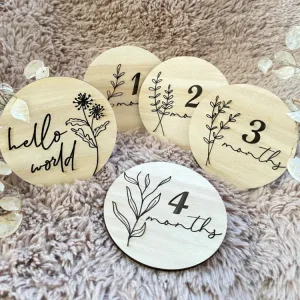 Flower anı kartlarından hello world ile 1, 2, 3 ve 4 months kartları, dal ve yaprak kazımalarıyla halı üzerinde