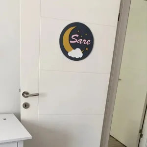Ay bulut temalı kapı süsü beyaz oda kapısında; lacivert zemin, altın hilal, beyaz bulut ve pembe renkli örnek isim