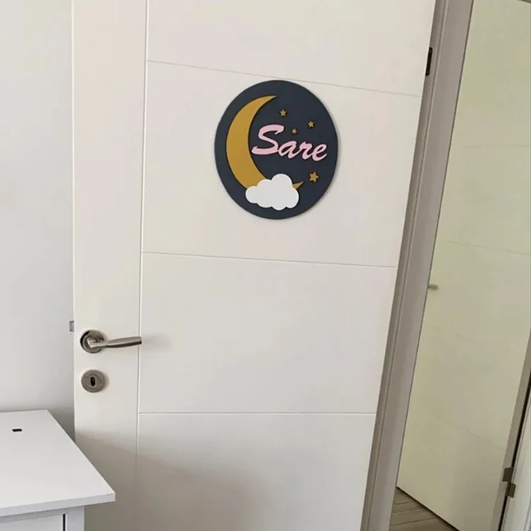 Ay bulut temalı kapı süsü beyaz oda kapısında; lacivert zemin, altın hilal, beyaz bulut ve pembe renkli örnek isim