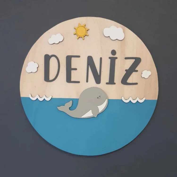Deniz temalı kapı süsü önden; ahşap üst zemin, mavi deniz, gri balina, beyaz dalga ve bulutlar, antrasit isim yazılı