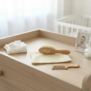Örnek isimli fırça, tarak ve krem çanta açık renk alt değiştirme ünitesinde; yanında katlı bebek giysisi ve çerçeve