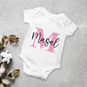 İsme özel bebek body pembe harfli modelde, siyah örnek isim yazılı, gri zeminde pamuk dalı ve kuru yapraklarla
