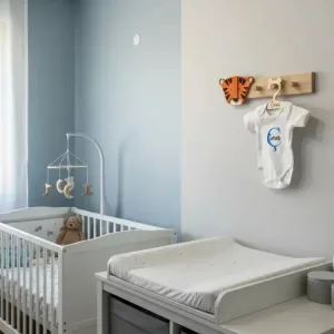 Kaplan duvar askısı bebek odasında alt açma masası üstünde; turuncu kaplan başı ve askıda isim yazılı bebek kıyafeti