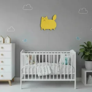 Kedi ahşap gece lambası, bulut ve kuş desenli gri duvarda beşiğin üstünde; gülümseyen sarı kedi figürü