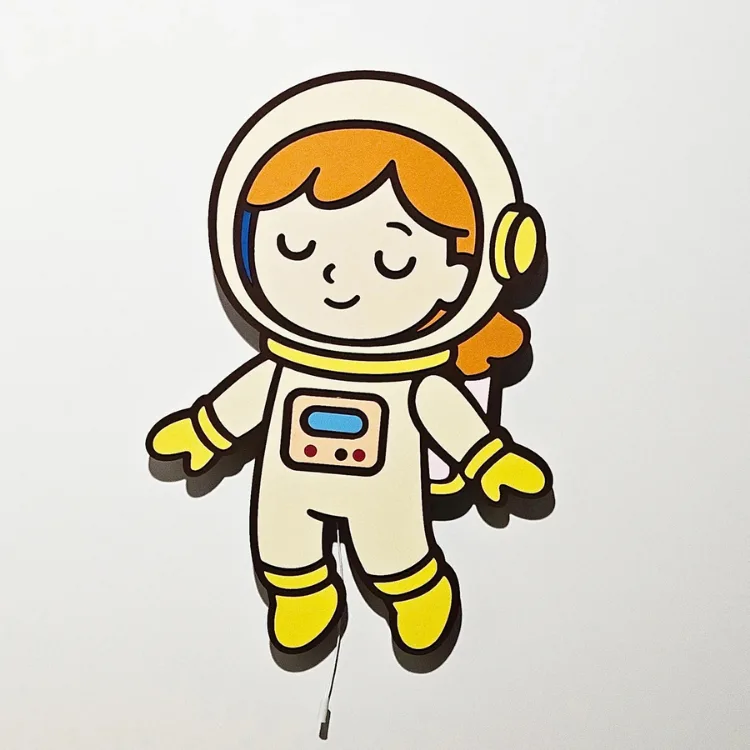 Kız Astronot lamba önden, ışığı kapalı; turuncu saçlı, sarı eldivenli ve botlu figür beyaz duvarda