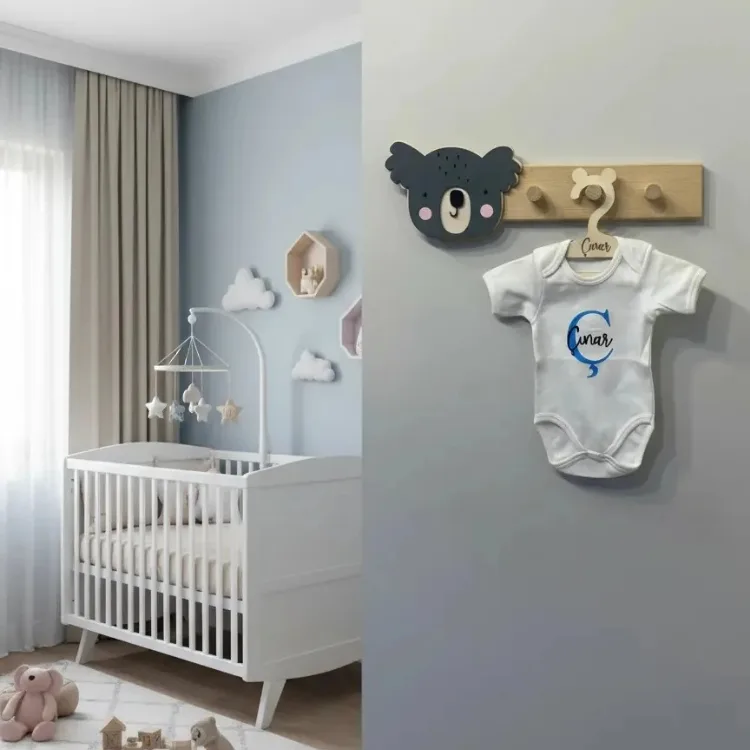Koala duvar askısı bebek odasında gri duvarda; antrasit koala başı ve askıda isim yazılı beyaz bebek kıyafeti