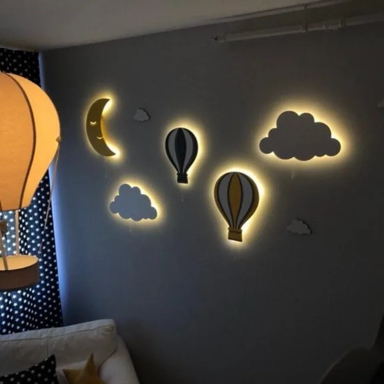 Karanlık odada yanan aydede, iki uçan balon ve iki bulut ahşap lamba, lacivert duvarda yakından