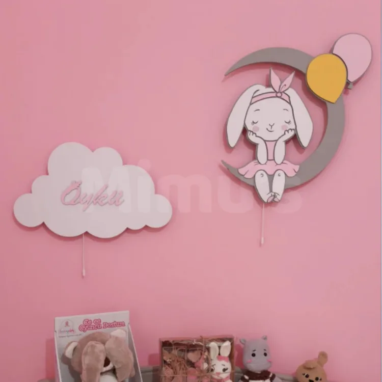 Pembe duvarda örnek isim yazılı bulut lamba ve balonlu tavşan ahşap lamba, altında oyuncak rafı