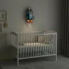 Sütlü roket ahşap gece lambası, loş bebek odasında beyaz beşiğin üstünde ışığı açık, MILK yazılı süt kutusu roket