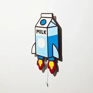 Sütlü Roket lambanın yandan görünümü, ışığı kapalı; MILK yazılı mavi süt kutusu, beyaz kanat ve alev detayları