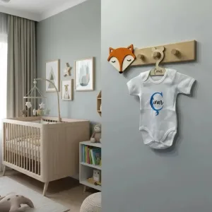 Tilki duvar askısı bebek odasında gri duvarda; uyuyan yüzlü turuncu tilki başı ve askıda isim yazılı bebek kıyafeti