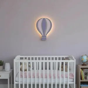 Uçan balon ahşap gece lambası, lila duvarda beyaz bebek karyolasının üzerinde ışığı açık, mor ve pembe dilimli