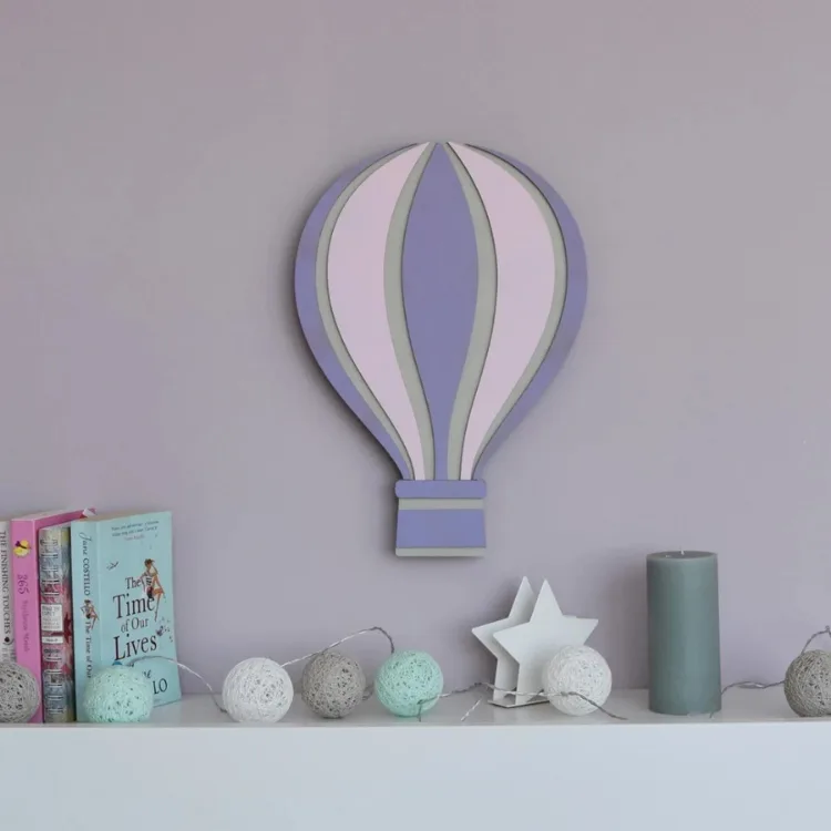 Uçan Balon lamba beyaz rafın üzerindeki lila duvarda; mor, pembe ve gri dilimler, yanında kitaplar